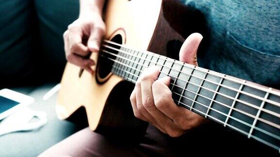 音乐家亚洲男性弹奏原声吉他唱歌学习练习悠闲的时间坐在客厅的沙发上度过活动职业