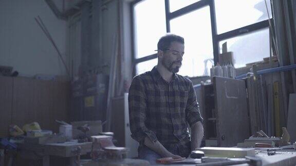 一个四十多岁的英俊男子在他的工作室里用木制工具工作比如一个周末在背光下用锯子和钻机