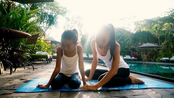 母亲和女儿在游泳池附近做瑜伽