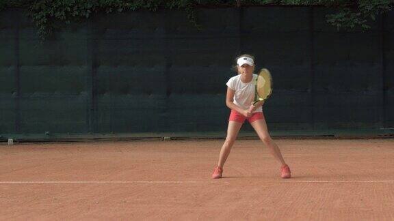 有竞争精神有决心有抱负的小女孩网球运动员在红色的球场上专注于比赛和拍子击球