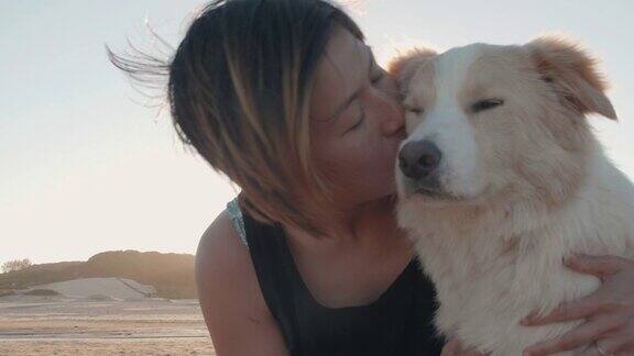 日落时分一个女人和她的宠物狗在海滩上