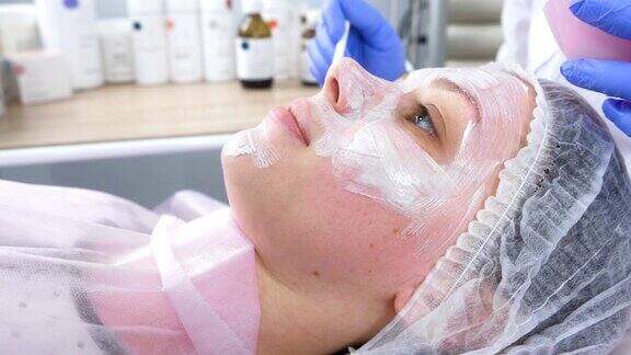 美容师用刷子在这位妇女脸上敷上白色面膜