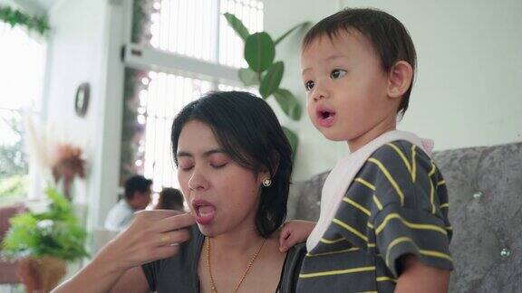 亚洲男婴和妈妈一起吃饭当母亲在餐厅喂食物时用手递给婴儿