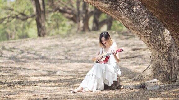 在公园里弹吉他的漂亮女人