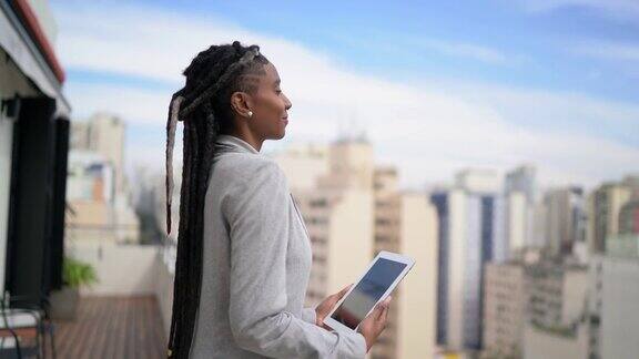 一位年轻的女商人在屋顶上思考和使用数字平板电脑