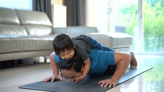 一个男人在家里背着开心的宝宝做俯卧撑
