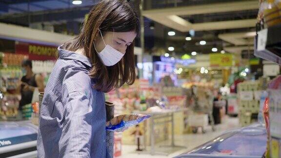 亚洲妇女带着一次性医用口罩在杂货店购物