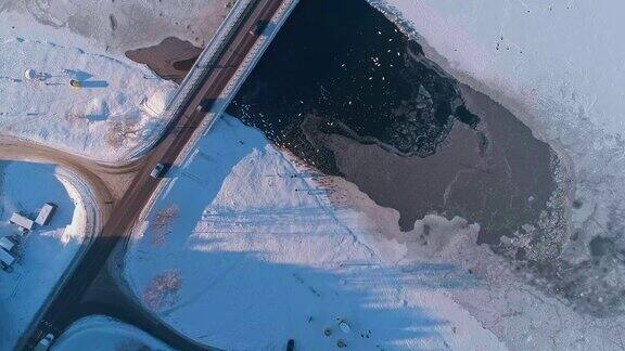 寒冷的冬天从上面俯瞰可以看到冰封的河流上的桥在开阔的水面上有一大群鸭子和天鹅无人机视频与静态摄像机