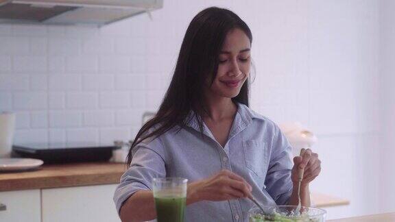 健康的亚洲妇女在家里的厨房里混合准备烹饪蔬菜沙拉素食主义者的素食概念