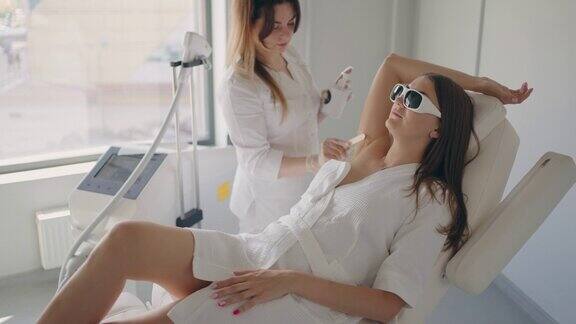 年轻女子在美容诊所激光脱毛腋下保护眼睛的墨镜