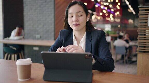女商人在咖啡馆的数字平板电脑上召开视频会议与她的同事进行视频通话