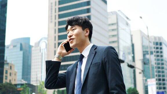 成年韩国商人在办公大楼附近使用手机