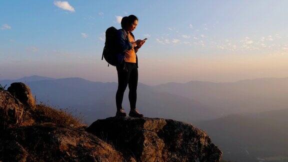 登山女子在山顶上使用手机交流