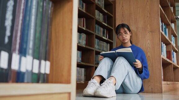 女学生坐在地板上读书在图书馆准备考试教育与学习理念