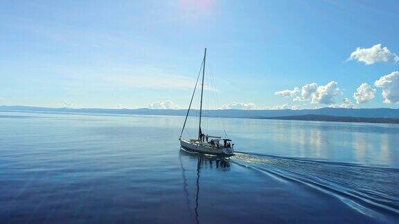 4K无人机实时拍摄宁静晴朗的蓝色海洋上的帆船