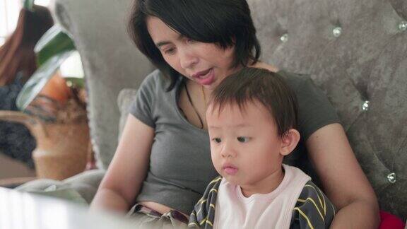 亚洲小男孩和妈妈一起坐在餐厅的沙发上阅读和看菜单食物