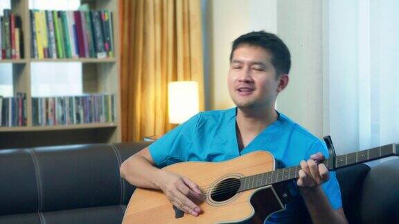 护士亚洲男工人喜欢在家里的沙发上弹吉他唱歌