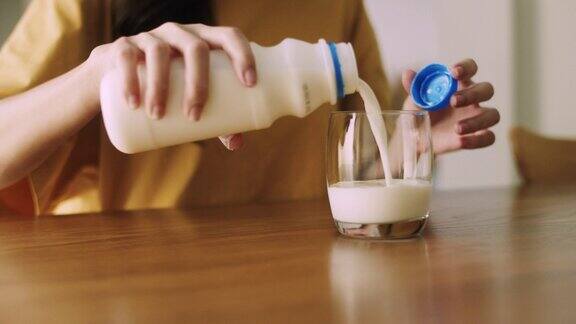 一名妇女在家里吃早餐时把牛奶倒进饮水杯