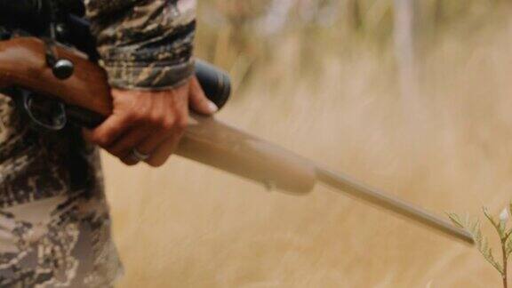 一个猎人小心翼翼地走过芦苇手里拿着步枪他跟踪他的猎物