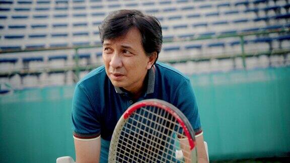 疲惫的老年人在网球场旁放松