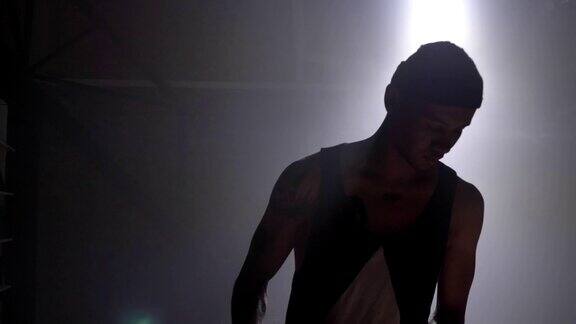 一个篮球运动员的剪影在黑暗朦胧的房间里用泛光灯打球