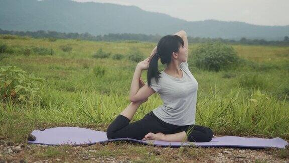 美丽的年轻亚洲女人在日出的山景进行精神瑜伽姿势