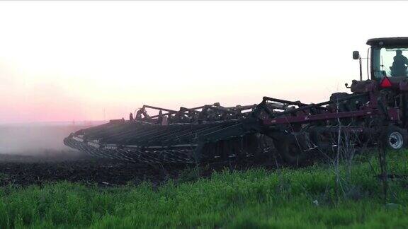 夕阳西下一辆红色拖拉机正在耕田准备播种未来的收成
