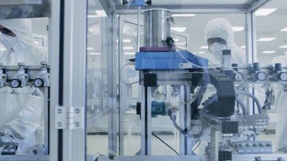 一组科学家穿着无菌防护服在现代工业3D打印机器上工作制药生物技术和半导体创造制造过程从内部拍摄