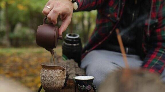 一名男子将深色的普洱茶从陶制茶壶倒入特制的陶制壶中