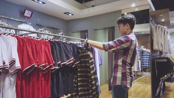 亚洲华人男性手拿男装衬衫在服装店选择正确的一件购物