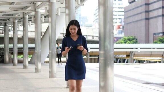 商业女性走路和使用智能手机