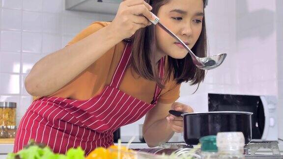 年轻的亚洲妇女在厨房做饭妻子正在为丈夫做一顿特别的饭