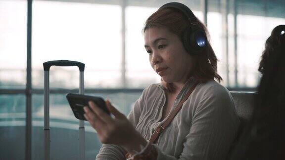 4K镜头候机乘客她在机场玩手机听音乐