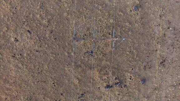 直接头顶拍摄的六旋翼无人机飞过电线上方的泥土和草地户外