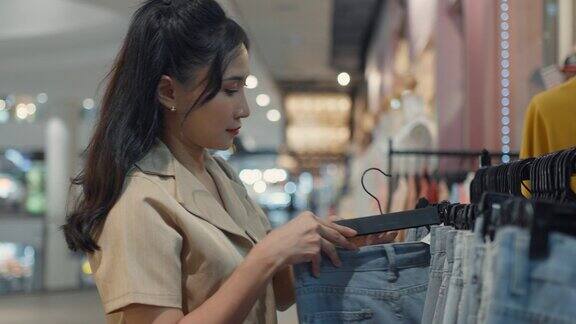 年轻女子穿着漂亮的休闲装提着许多纸质购物袋在购物中心走着穿着衣服和鞋子