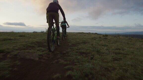 两名骑手(一名女性和一名男性)山地自行车在洛基山脉以西的丹佛科罗拉多州日出