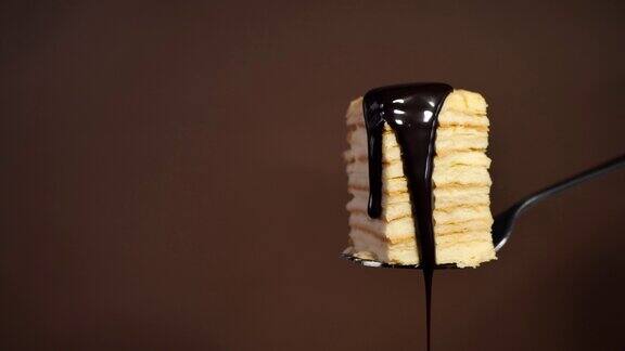 把蛋糕放在叉子上在棕色的背景上浇上巧克力酱