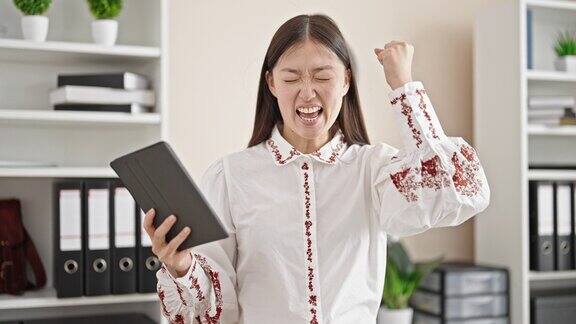 年轻的中国女商务工作者在办公室用触控板脸上带着胜利者的表情
