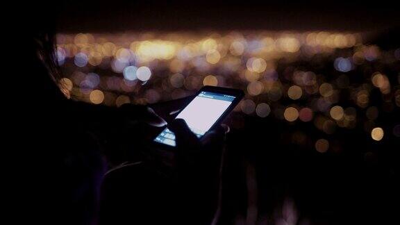 晚上在户外用手机发送短信的人