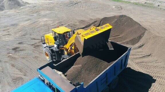 拖拉机用水桶把沙子和碎石装进机器里