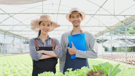 亚洲农民夫妇在蔬菜水培农场工作的肖像有魅力的青年男女农家感到骄傲和自信的工作后在温室与幸福的看着相机