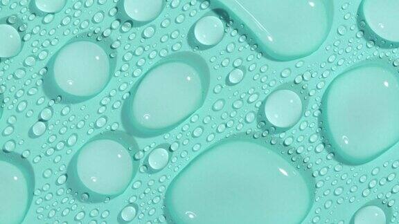 微距镜头的化妆品保湿液滴在绿色蓝色粉彩背景旋转透明化妆品凝胶液玻尿酸