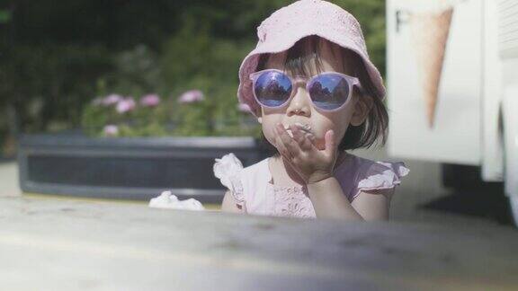 初学走路的小女孩在夏日公园吃冰淇淋