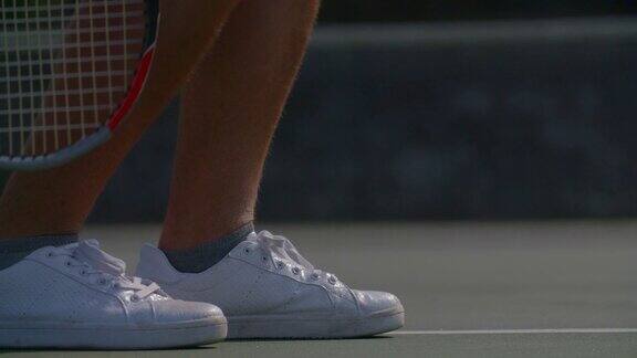 一名网球运动员将球和网球鞋弹起并发球