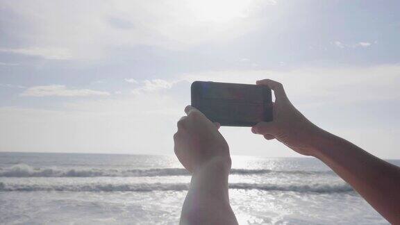 度假时在海边的海滩上用智能手机拍照