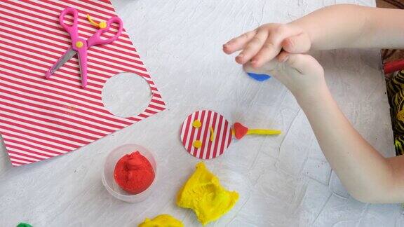 小女孩用五颜六色的泥面团、橡皮泥和纸制作有趣的玩具家庭教育游戏