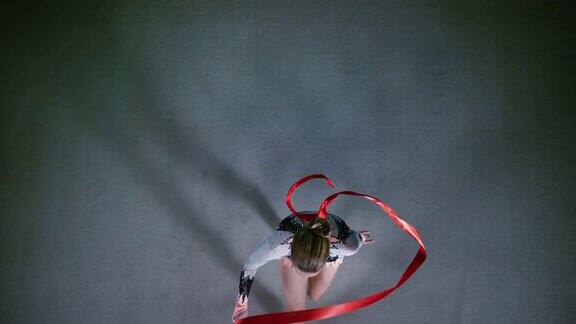 SLOMOLD上方一名艺术体操运动员旋转着红丝带走过地板