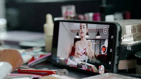 亚洲年轻女孩博客录制自拍视频与化妆口红化妆品在家在线影响社交媒体概念-股票形象
