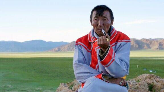 身着传统服饰的蒙古族牧民在西部阿尔泰山附近抽烟