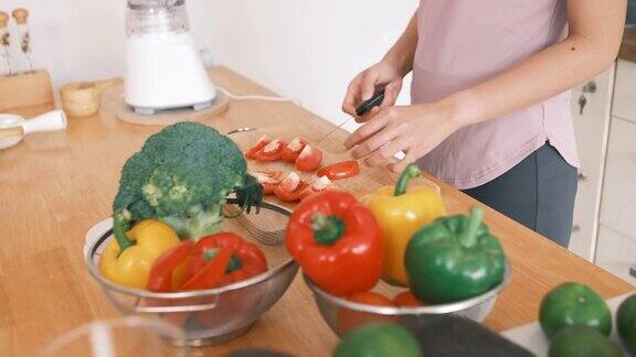 年轻女子的手在厨房里切西红柿做沙拉